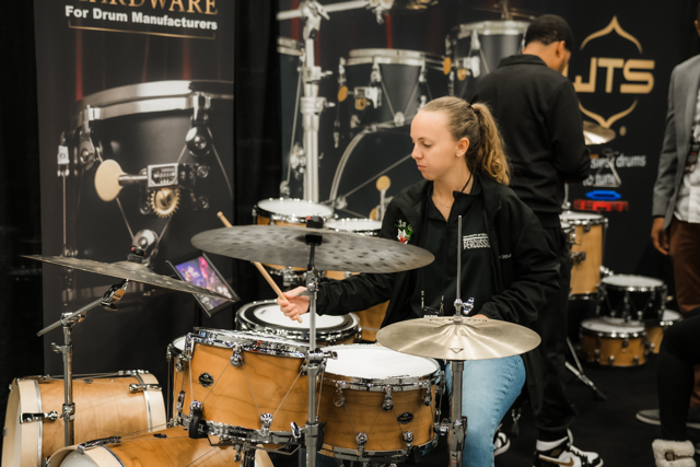 PASIC Expo Hall in 2025, woman tests drumset